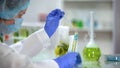 Scientist adding blue liquid in tube with yellow oily substance, biofuel testing