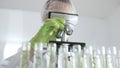 Scientist analyzing test tubes, wearing green protective gear while working with microscope in sterile laboratory Royalty Free Stock Photo