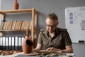 Scientist archaeologist working in office reading book studying ancient vase from textbook