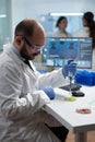 Scientist biologist man putting chemical fluid in petri dish using medical micropippete