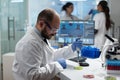 Scientist biologist man putting chemical fluid in petri dish using medical micropippete