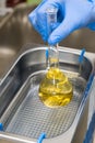 Scientist in blue rubber puts a yellow solution in the flask for dissolving or extraction into ultrasound bath. Urea Royalty Free Stock Photo