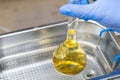 Scientist in blue rubber puts a yellow solution in the flask for dissolving or extraction into ultrasound bath. Urea Royalty Free Stock Photo