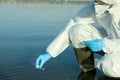 Scientist in chemical protective suit with test tube taking sample from river for analysis, closeup Royalty Free Stock Photo