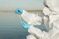 Scientist in chemical protective suit with test tube taking sample from river for analysis Royalty Free Stock Photo