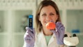 Scientist chemist holding in hands tangerine and device for measuring amount of nitrates in chemical laboratory closeup Royalty Free Stock Photo