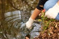 A scientist collects river water in a glass beaker