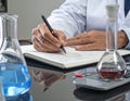 Scientist Conducting Laboratory Experiment with Glassware and Notebook Royalty Free Stock Photo