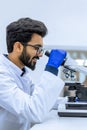 Scientist conducts experiments, adjusts specimen in petri dish and looking on it into microscope Royalty Free Stock Photo