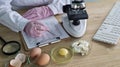 Scientist conducts research on egg samples using a microscope and a clipboard in a laboratory Royalty Free Stock Photo