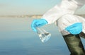 Scientist with conical flask taking sample from river for analysis, closeup Royalty Free Stock Photo