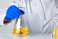 Scientist or doctor in blue gloves pouring some yellow liquid into a flask Royalty Free Stock Photo