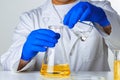 Scientist or doctor in blue gloves pouring some yellow liquid into a flask Royalty Free Stock Photo