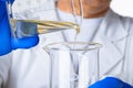 Scientist or doctor in blue gloves pouring some yellow liquid into a flask Royalty Free Stock Photo