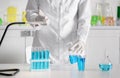 Scientist dripping color liquid into flask in laboratory