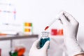 Scientist dripping reagent into bottle with sample in chemistry laboratory, closeup