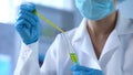 Scientist dripping yellow liquid in lab tube and looking at reaction, experiment