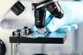 Scientist examining sample of red liquid on slide under microscope in laboratory, closeup Royalty Free Stock Photo