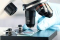 Scientist examining sample of red liquid on slide under microscope in laboratory, closeup Royalty Free Stock Photo