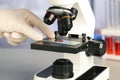 Scientist examining sample of red liquid on slide under microscope in laboratory, closeup Royalty Free Stock Photo