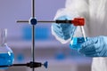 Scientist fixing flask on stand in laboratory, closeup