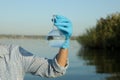 Scientist with florence flask taking sample from river for analysis, closeup Royalty Free Stock Photo