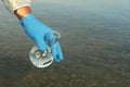 Scientist with florence flask taking sample from river for analysis, closeup Royalty Free Stock Photo