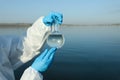 Scientist with florence flask taking sample from river for analysis, closeup Royalty Free Stock Photo