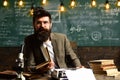 Scientist in glasses type on vintage typewriter. Scientist with beard typewrite research paper with microscope and books