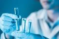 Scientist hand hold test tubes filled with blue sample chemicals in chemistry science laboratory. Glassware in medical research. Royalty Free Stock Photo