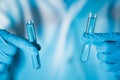 Scientist hand hold test tubes filled with blue sample chemicals in chemistry science laboratory. Glassware in medical research. Royalty Free Stock Photo