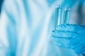 Scientist hand hold test tubes filled with blue sample chemicals in chemistry science laboratory. Glassware in medical research. Royalty Free Stock Photo