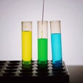 Scientist hand pouring a green chemical solution from a laboratory glass test tube into a scientific cylinder with yellow liquid f Royalty Free Stock Photo