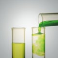 Scientist hand pouring a green chemical solution from a laboratory glass test tube into a scientific cylinder with yellow liquid f Royalty Free Stock Photo