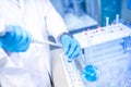 Scientist hands with dropper or pipette, examining samples and blue liquid