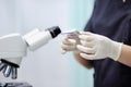 Scientist hands holding samples liquid with microscope on background