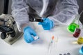 Scientist in hazmat suit and goggles holding vaccine bottle and magnifying glass, looking and research. Epidemiology virus test. Royalty Free Stock Photo