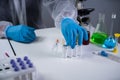 Scientist holding ampule with white powder, illegal pharmacy production, drugs. Laboratory assistant examines glass medical