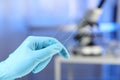 Scientist holding clean glass microscope slides in laboratory, closeup