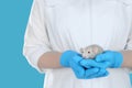 Scientist holding rat on light blue background, closeup. Animal testing concept