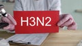 Scientist holding a red card with H3N2 written on it in a lab Royalty Free Stock Photo