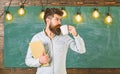 Scientist holds book and drinks coffee, chalkboard on background, copy space. Man with beard on calm face in classroom Royalty Free Stock Photo