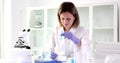 Scientist holds test tube with blue liquid and writes down obtained chemical data