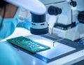 Scientist inspecting a circuit board under a microscope in a laboratory setting Royalty Free Stock Photo