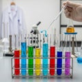 Scientist in lab adding liquid to test tubes with colorful solutions Royalty Free Stock Photo