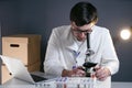 Scientist in lab coat and eyeglasses working at workplace with laptop in laboratory. Male doctor researcher are doing Royalty Free Stock Photo