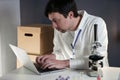 Scientist in lab coat and eyeglasses working at workplace with laptop in laboratory. Male doctor researcher are doing Royalty Free Stock Photo