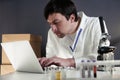 Scientist in lab coat and eyeglasses working at workplace with laptop in laboratory. Male doctor researcher are doing Royalty Free Stock Photo