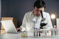 Scientist in lab coat and eyeglasses working at workplace with laptop in laboratory. Male doctor researcher are doing Royalty Free Stock Photo