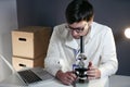 Scientist in lab coat and eyeglasses working at workplace with laptop in laboratory. Male doctor researcher are doing Royalty Free Stock Photo
